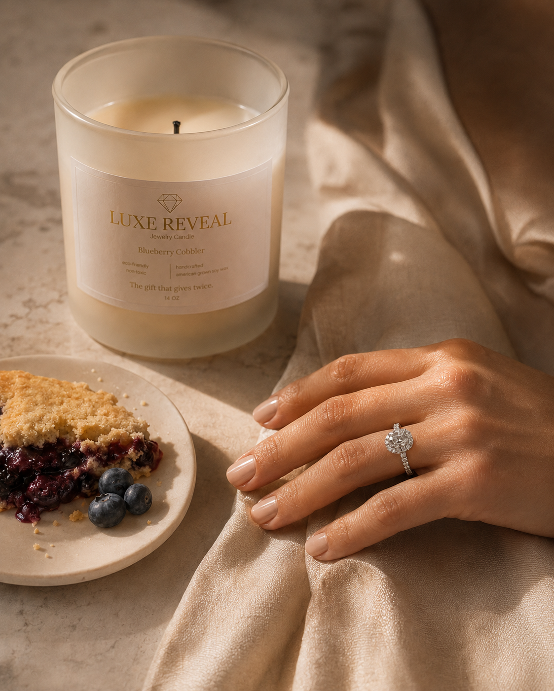 The revealed Luxe Reveal diamond ring worn beside the Blueberry Cobbler candle and blueberry cobbler
