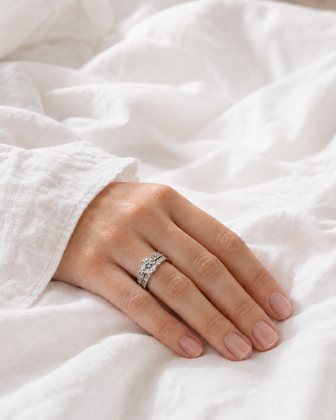 The revealed Luxe Reveal diamond ring worn on the hand over white cotton bedding