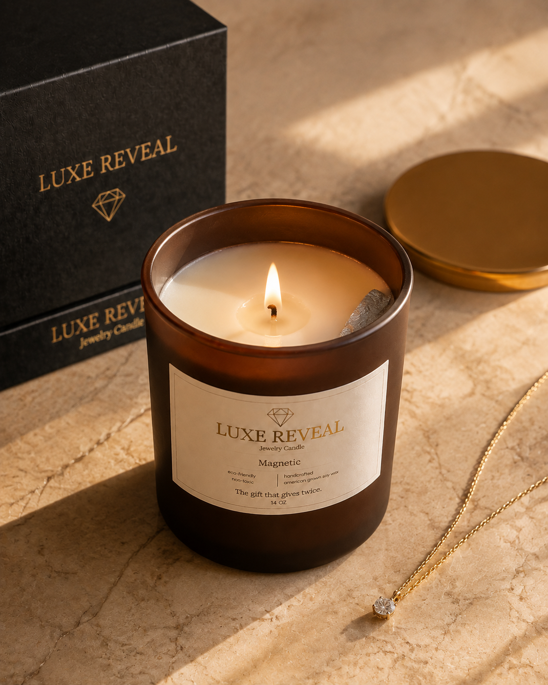 Lit brown Magnetic Luxe Reveal candle on marble with the black gift box and the revealed gold diamond necklace