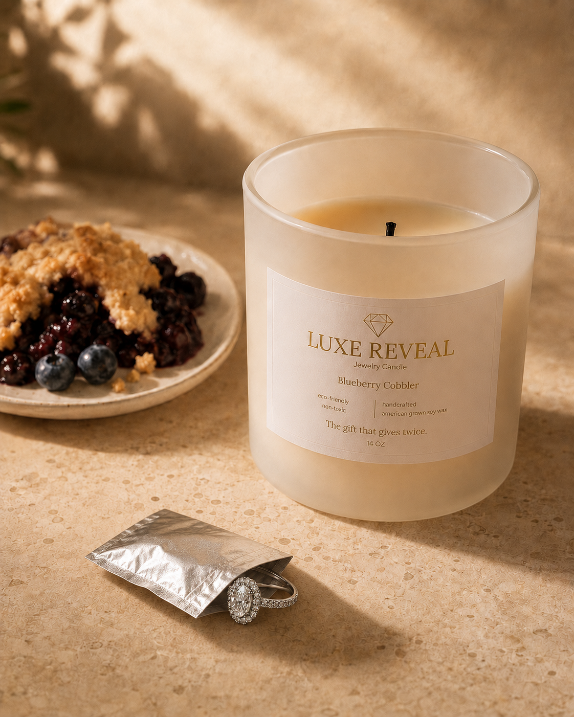 Ring emerging from the small silver protective pouch beside the lit Blueberry Cobbler candle and blueberry cobbler