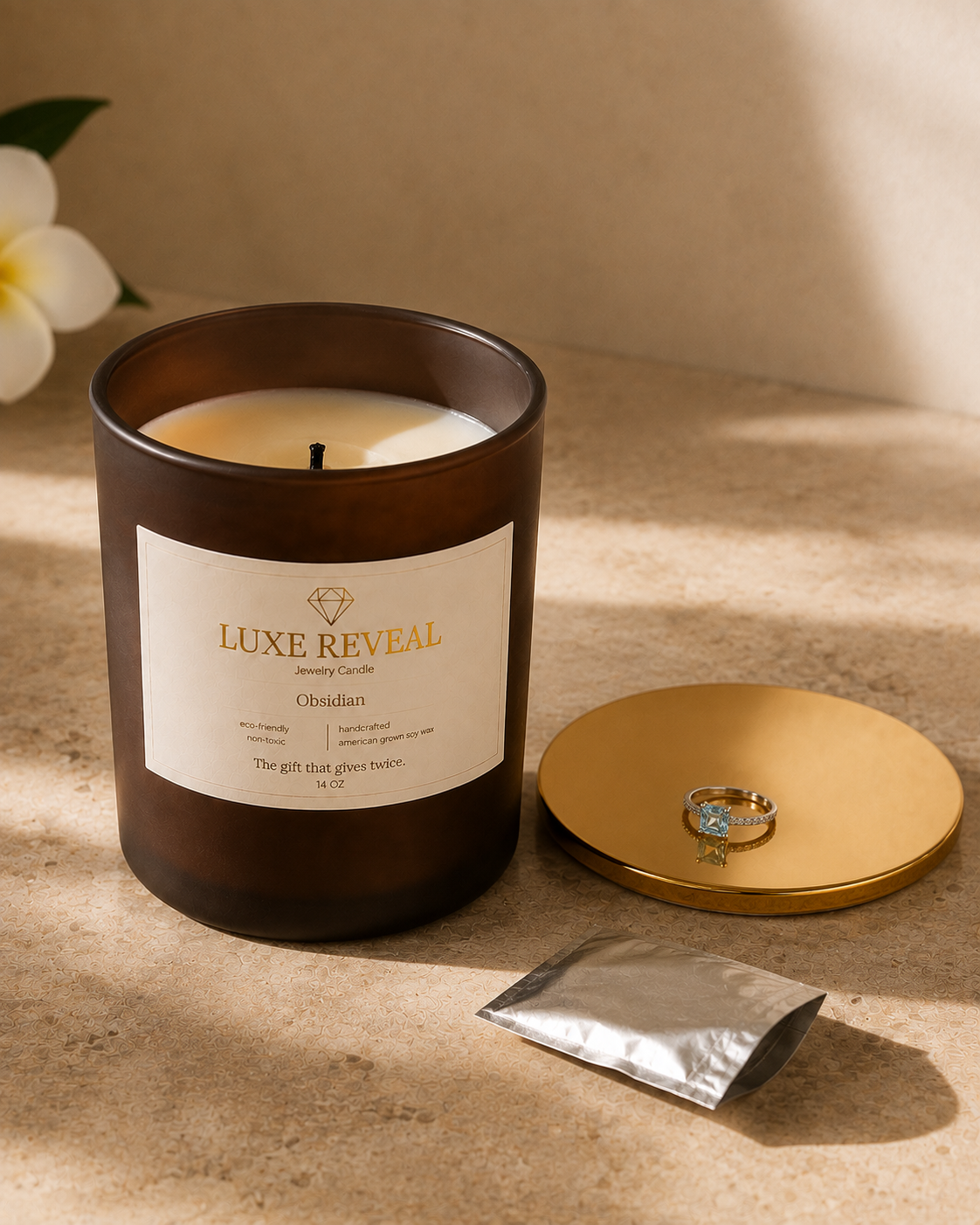Open Obsidian Luxe Reveal candle with the silver foil pouch and the aqua gemstone ring displayed on the gold lid