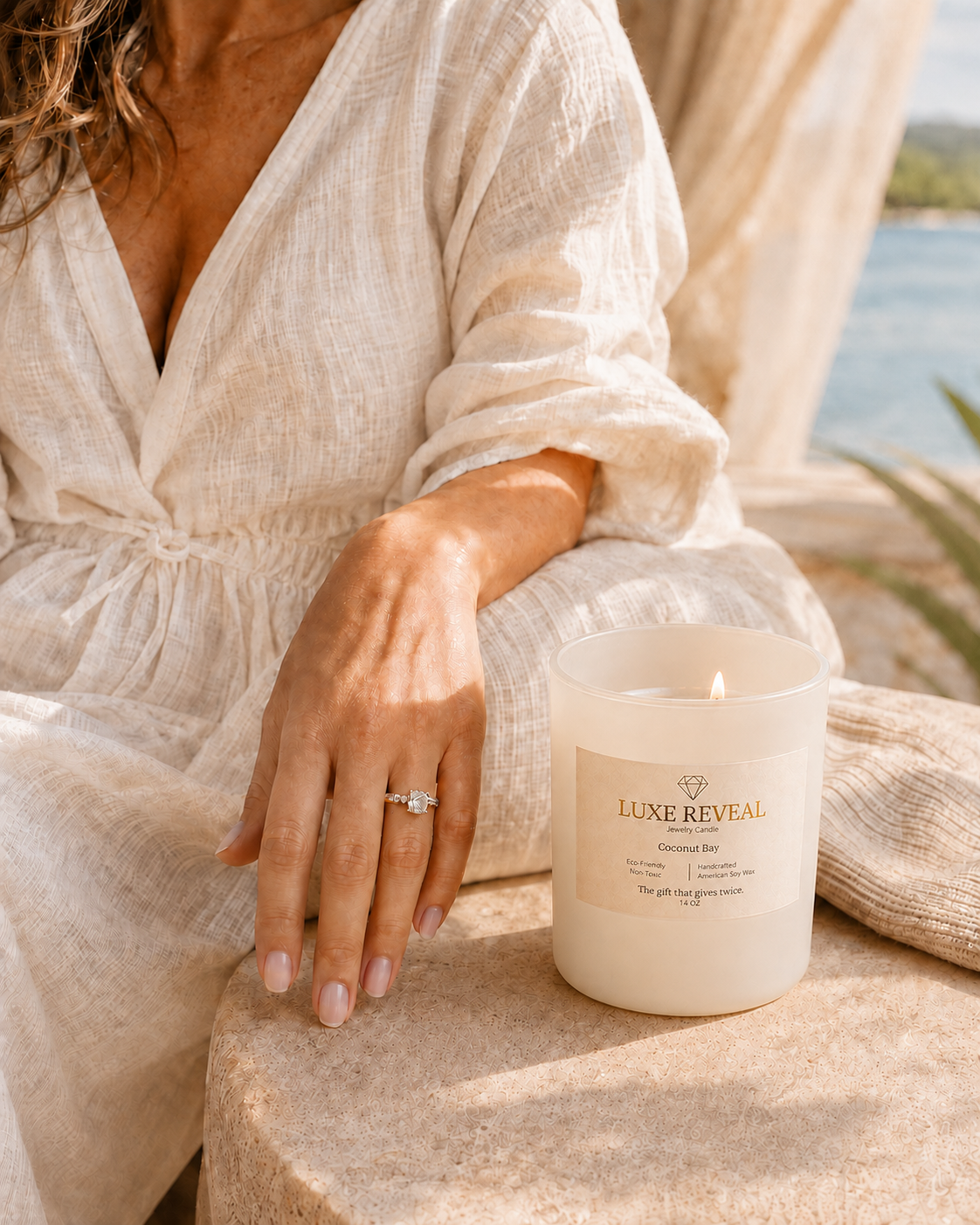 Woman in a cream linen outfit wearing her revealed diamond ring beside a nearly finished Ivory Coconut Bay candle