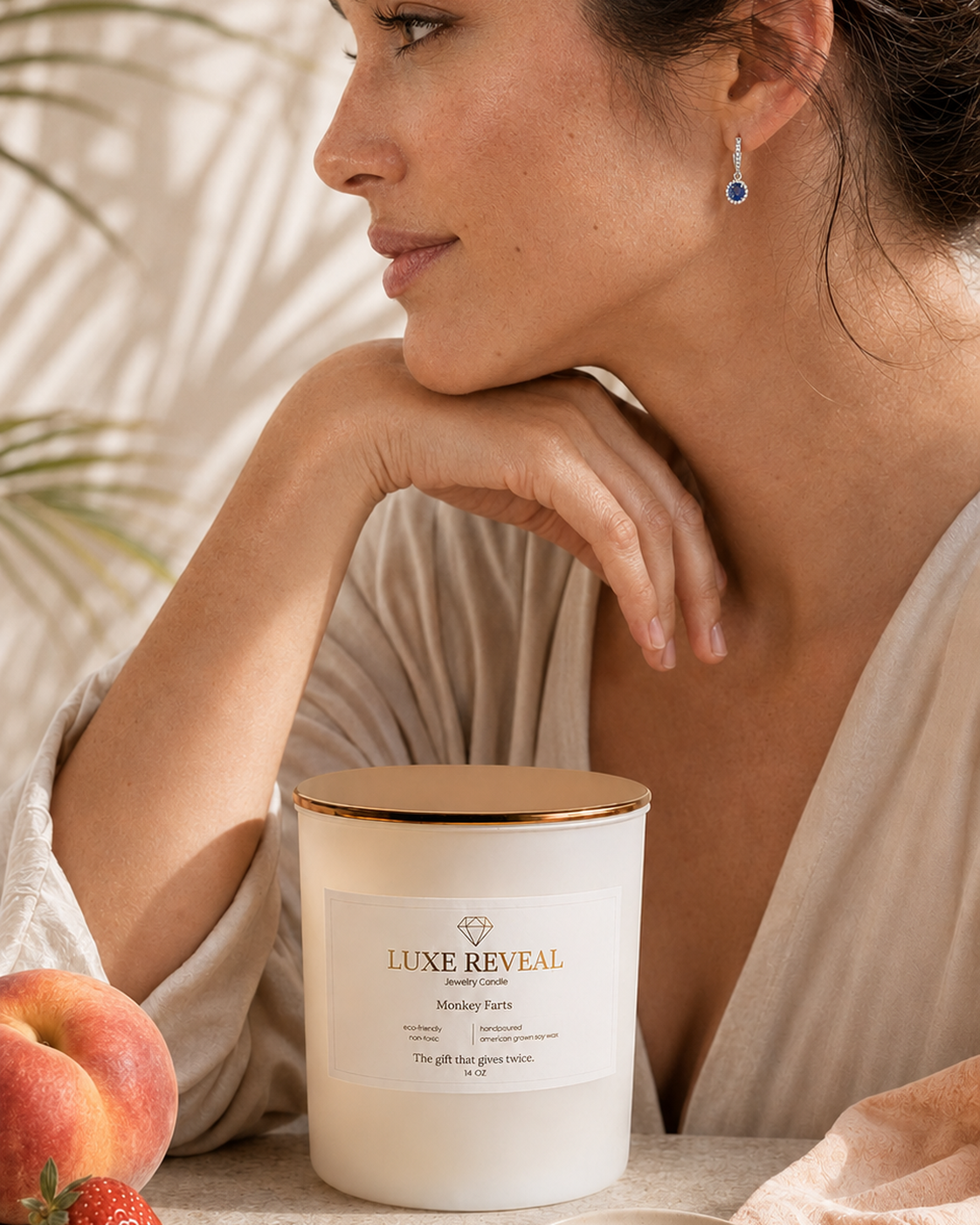 Model wearing the revealed blue sapphire earring beside the Monkey Farts Luxe Reveal candle