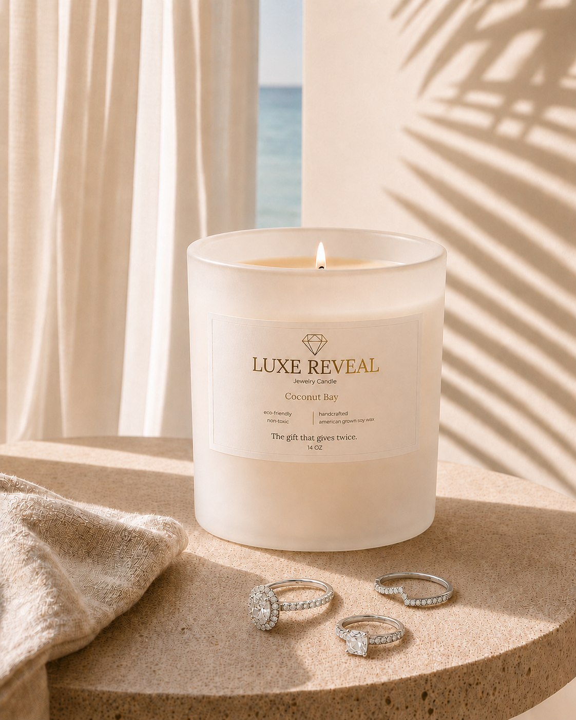 Lit Coconut Bay Luxe Reveal candle with delicate diamond rings displayed beside the gift box